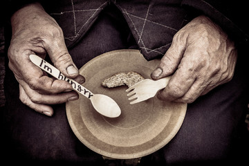 Male worker. He holds a paper plate in his lap. He is holding a wooden spoon and fork.