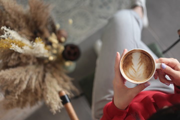 A lady sitting on a chair and holding a cup of coffee in a coffeeshop