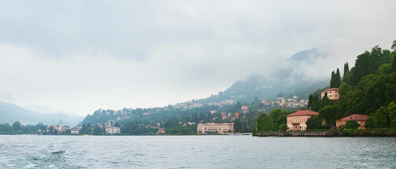 Panoramic view of Como lake with villages and mountains shrouded in clouds. Cernobbio. Italy.