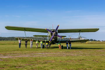 Fototapeta na wymiar Old bi-plane being pushed back by an airfield crew