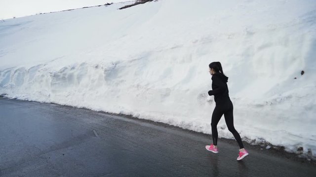 Determined energetic female jogger practicing in deep snow in the mountain