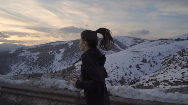 Female runner with ponytail jogging on sunset in cold winter evening