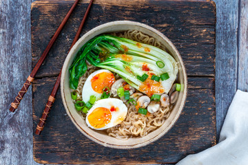 Japanese sesame ramen noodles with pok choi, boiled egg, mushrooms, spring onions and chili sauce - overhead view