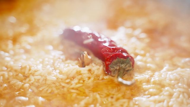 Uzbek national dish pilaf in a cauldron, red chili pepper, cooking, rice. Chili pepper close up.