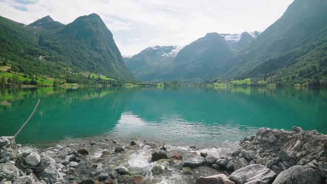 creek entering the beautiful olden lake in norway - beautiful green water and mountain surroundings
