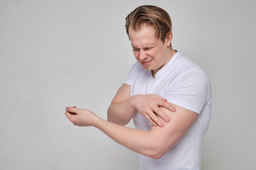 A man is in pain from contracting his arm muscles - biceps.