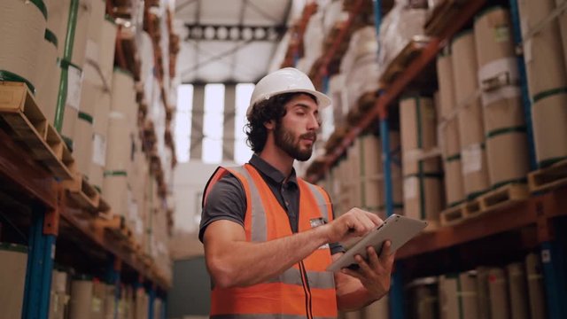 Warehouse worker checking inventory in stock room of a manufacturing company on touchscreen tablet