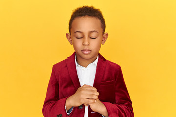 Isolated shot of African American little boy covering eyes and squeezing fist, trying to breathe...