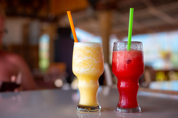 Watermelon and pineapple smoothie in a glass with straws, soft drink on a summer day