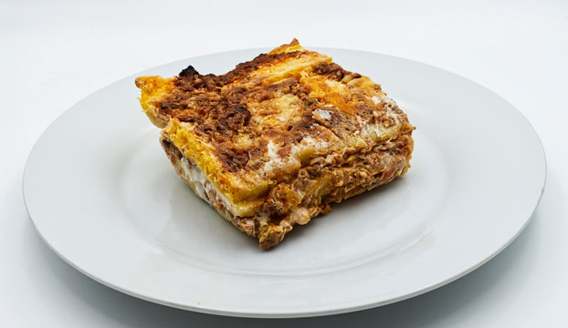 Slice of traditional italian Lasagne on a white plate.