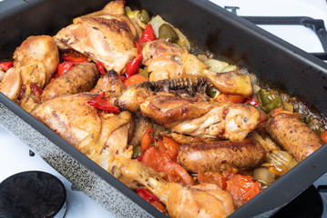 Chicken scarpariello close-up in a baking sheet - chicken with sausages, peppers, onions and pomiodors. American recipe for Italian food.