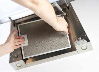 Men's hands remove the grease filter from the kitchen hood.Remove the filters from the hood.
