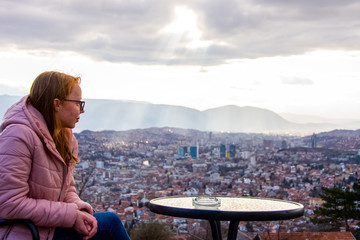 Fototapeta na wymiar Woman sitting and drinking coffe above Sarajevo