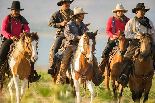 Western cowboys riding horses along the river.