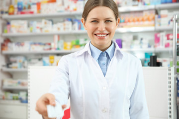 Professional pharmacist with pills in modern drugstore