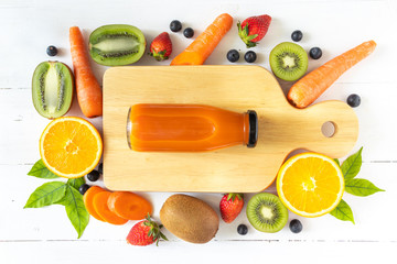 Carrot juice in a glass bottle on white wooden background, flay lay view of natural source of...
