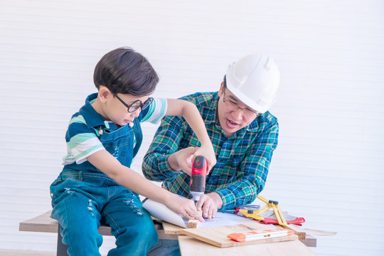 Father and son is drilling wood on workshop table for home improvement, for family bonding father and son love concept