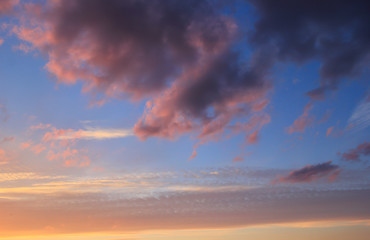 Spring blue sky at sunset with gray clouds.