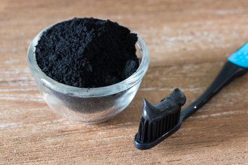 Close up view of black charcoal toothpaste and toothbrush ion wooden background