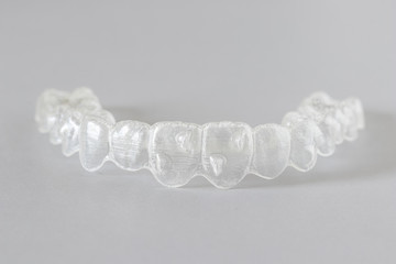 Close up view of invisalign braces or invisible retainers on grey background, new orthodontic equipment