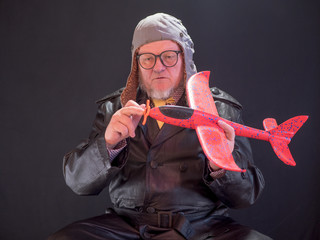 Portrait of strange elderly man has red airplane in his hands and torque spinner of apropeller....