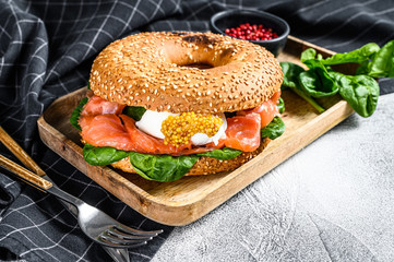 Healthy freshly baked bagel filled with smoked salmon, spinach and egg.  Gray background. Top view