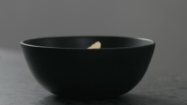 Slow motion round corn chips falling into black bowl closeup
