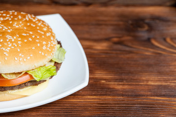 Burger on a plate and wooden background. Copy space.
