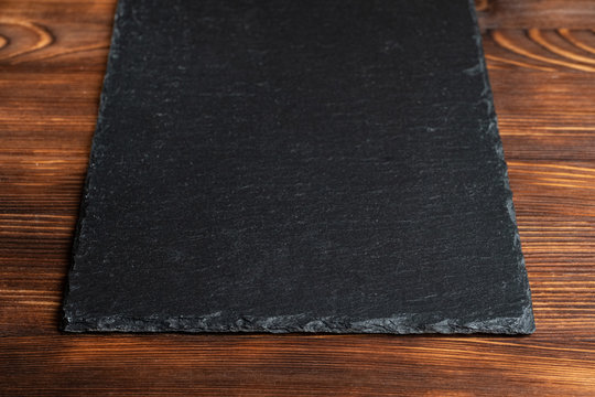 Crockery slate, black stone on a wooden background.