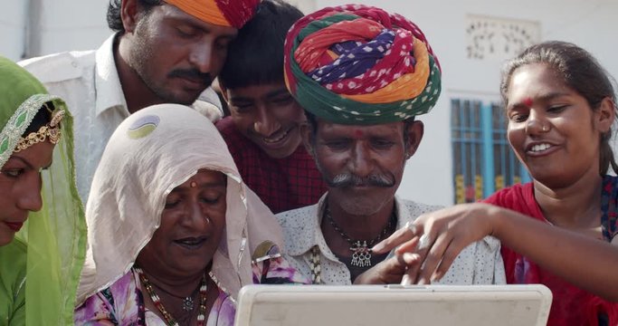 Traditional Rajasthani family, elders learning how to use a portable laptop from their educated lovely daughter with pride and happiness as they share and get entertained, learn,  enjoy as fascination