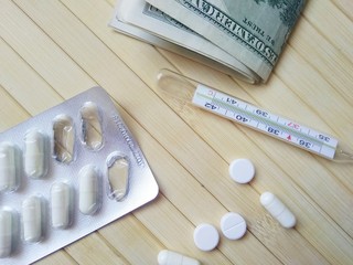pills and thermometer on wooden background