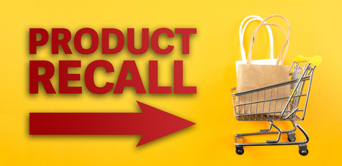 red text PRODUCT RECALL and arrow symbol against yellow background with shopping cart filled with...