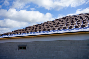 A close up of the partially finished roof of a new home being built. The roof decking is in place, and roof tiles are stacked neatly waiting to be installed.