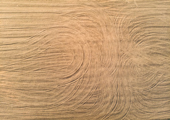 Aerial view of plowed agricultural crop field with the traces of vehicles left during the processing of the field