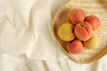 Ripe peaches in basket on cavas top view background