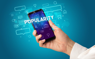 Female hand typing on smartphone with POPULARITY inscription, social media concept