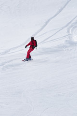 Fototapeta na wymiar Snowboarder in red descends on snowy ski slope