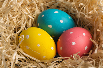 Colorful polka dot Easter eggs in wooden nest, greeting card, angle view