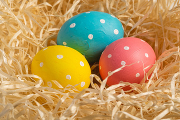 Colorful polka dot Easter eggs in wooden nest, greeting card, angle view