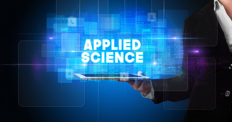 Young business person working on tablet and shows the inscription: APPLIED SCIENCE