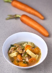 Chicken vegetable soup in white bowl, Indonesian food on a gray background