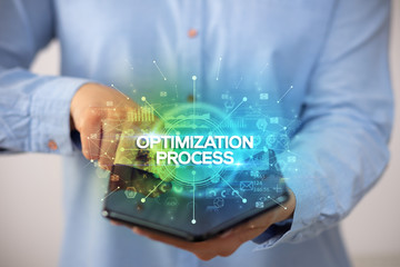 Businessman holding a foldable smartphone with OPTIMIZATION PROCESS inscription, new business concept