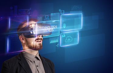 Businessman looking through Virtual Reality glasses with TECHNOLOGY TRENDS inscription, new technology concept