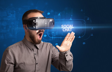 Businessman looking through Virtual Reality glasses with SOCIAL CHAT inscription, social networking concept