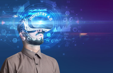 Businessman looking through Virtual Reality glasses with INDUSTRY 4.0 inscription, innovative technology concept