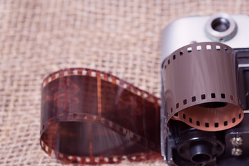 Old analog camera. Photographic film in a roll. Background from the canvas.