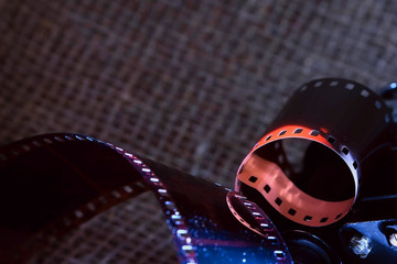An old film reflects light in the dark. Film strip against a dark background, artistic lighting.