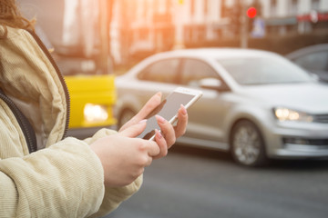 The girl's hands stand near the road and call a taxi using her phone