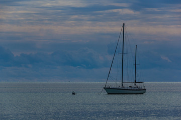 Sunset and blue hour with a sailing boat on the horizon