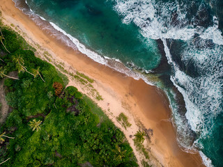Aerial view of a beach coastline with tropical lush, white and yellow sand and dramatic breaking waves, Galle, Sri Lanka